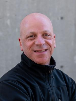 Bald man wearing black zip-up pullover