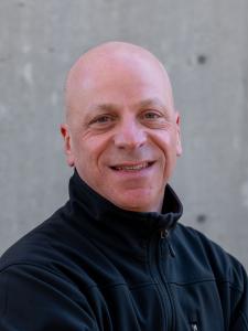 Bald man wearing black zip-up pullover