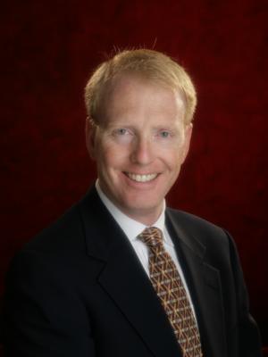 Dr Tubby, a middle-aged white man with short red hair wearing a suit