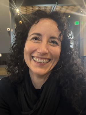 Woman with long curly brown hair wearing a black top