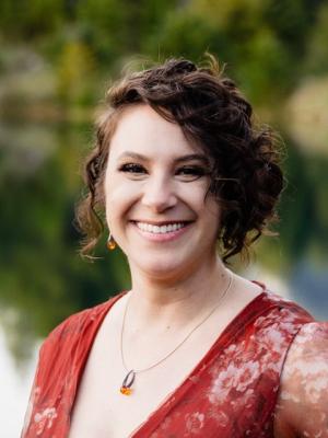 Person with short curly brown hair wearing red flower-patterned top
