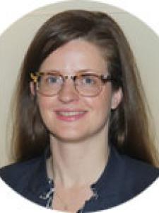 Headshot of Katrin Burkart, a young white woman with tortoiseshell glasses and long brown hair