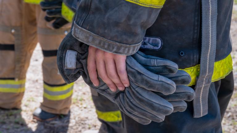 Close-up image of bare hands holding firefighter gloves.